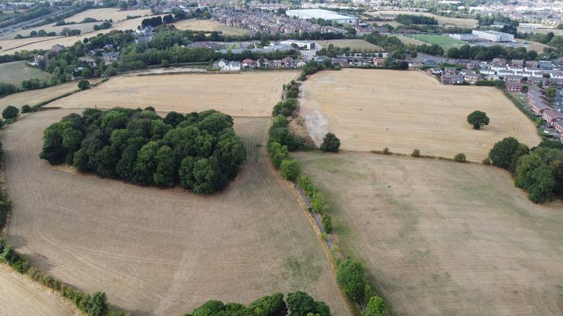 The fields from the south after harvest, stubble golden, with the town beyond.